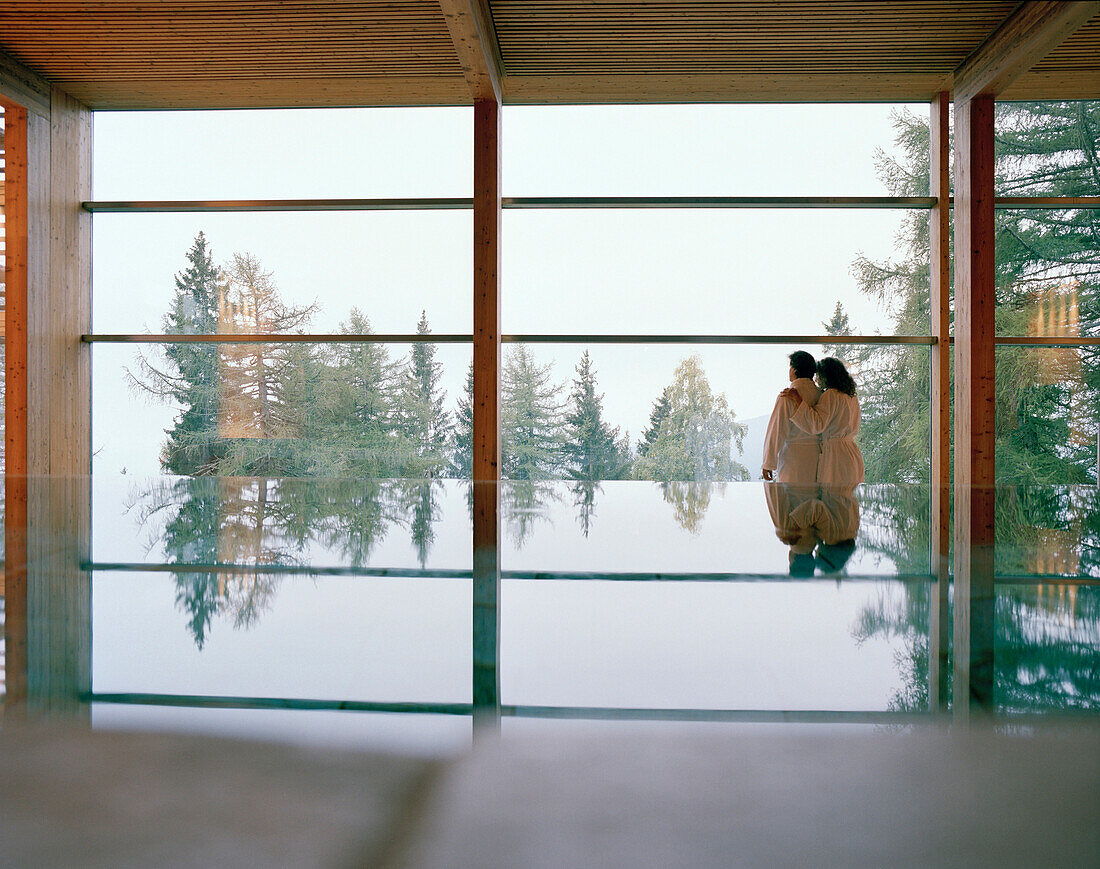 Couple near indoor pool looking out of a panorama window, Vigiljoch, Lana, Trentino-Alto Adige, South Tyrol, Italy