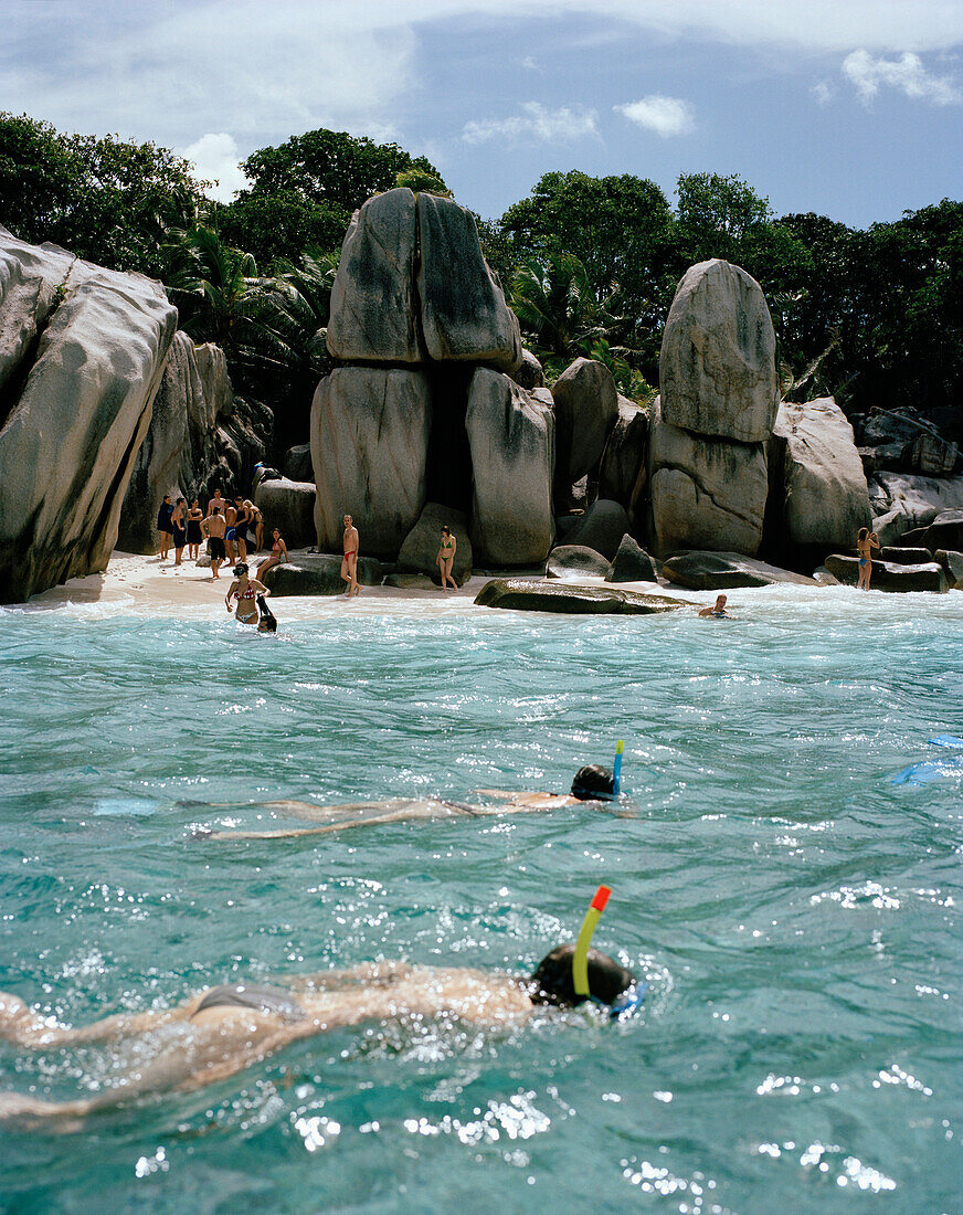 Menschen schnorcheln über Korallen vor der winzigen Insel Coco Island, La Digue and Inner Islands, Republik Seychellen, Indischer Ozean