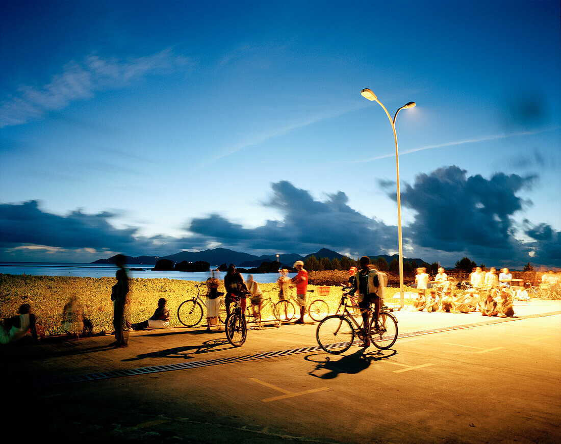People meeting on the pier in the evening, meeting point at night because of street lights, harbour of La Passe, La Digue, La Digue and Inner Islands, Republic of Seychelles, Indian Ocean