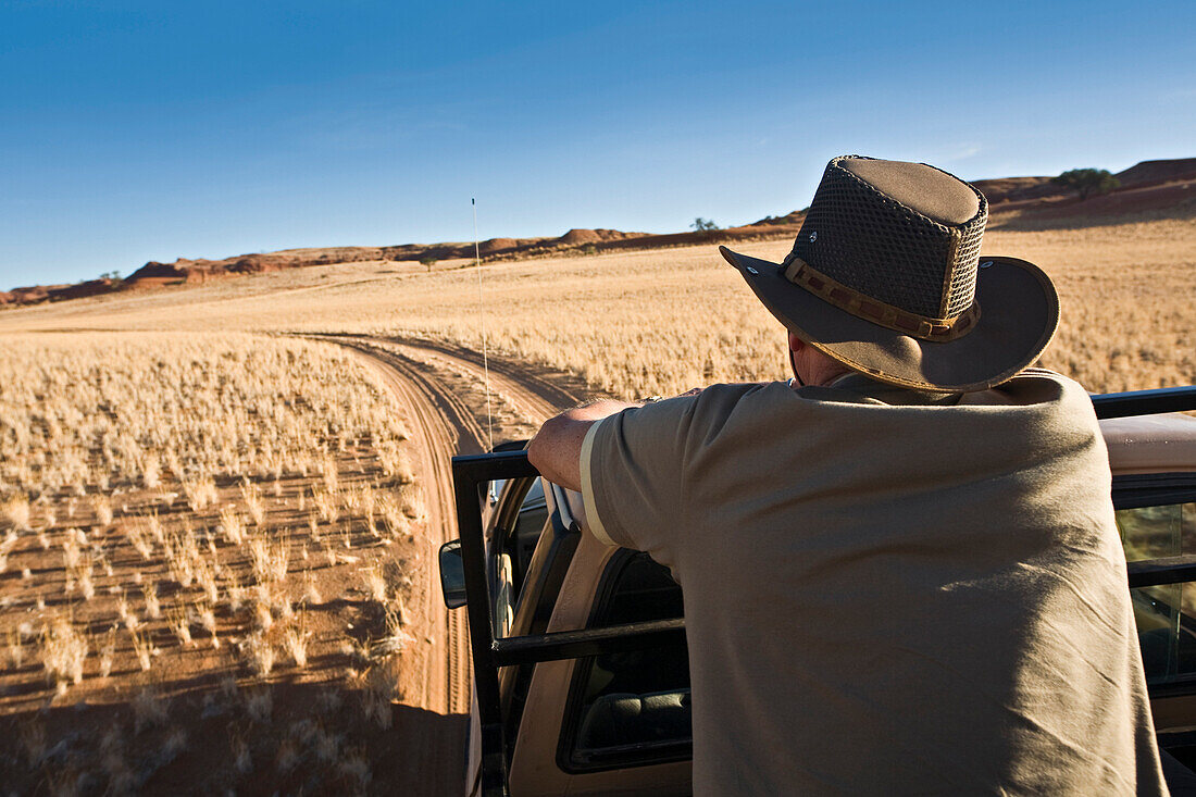 Mann mit Geländewagen im Namib Naukluft Nationalpark, Namibia, Afrika