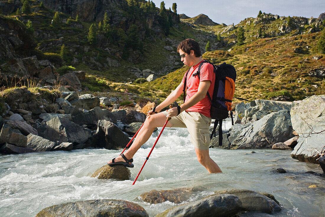 Young man crossing a stream, Oetztal Alps, Tyrol, Austria, Europe
