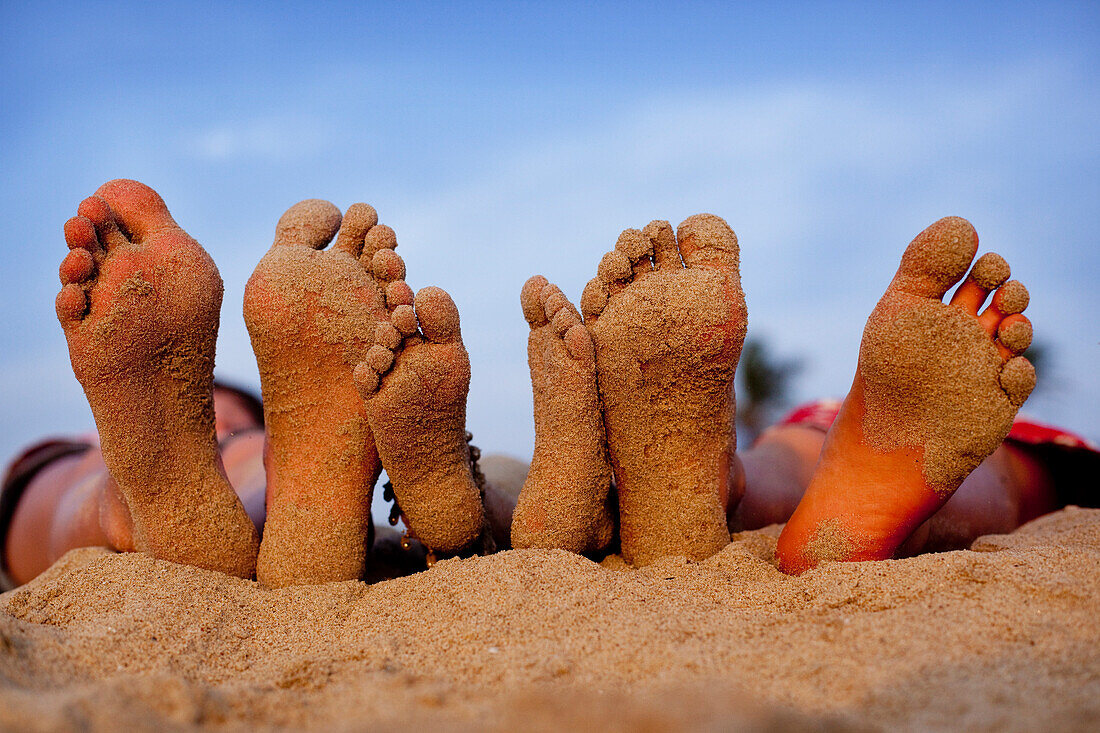 Sandy children's feet, Patnum Beach, Goa, India.