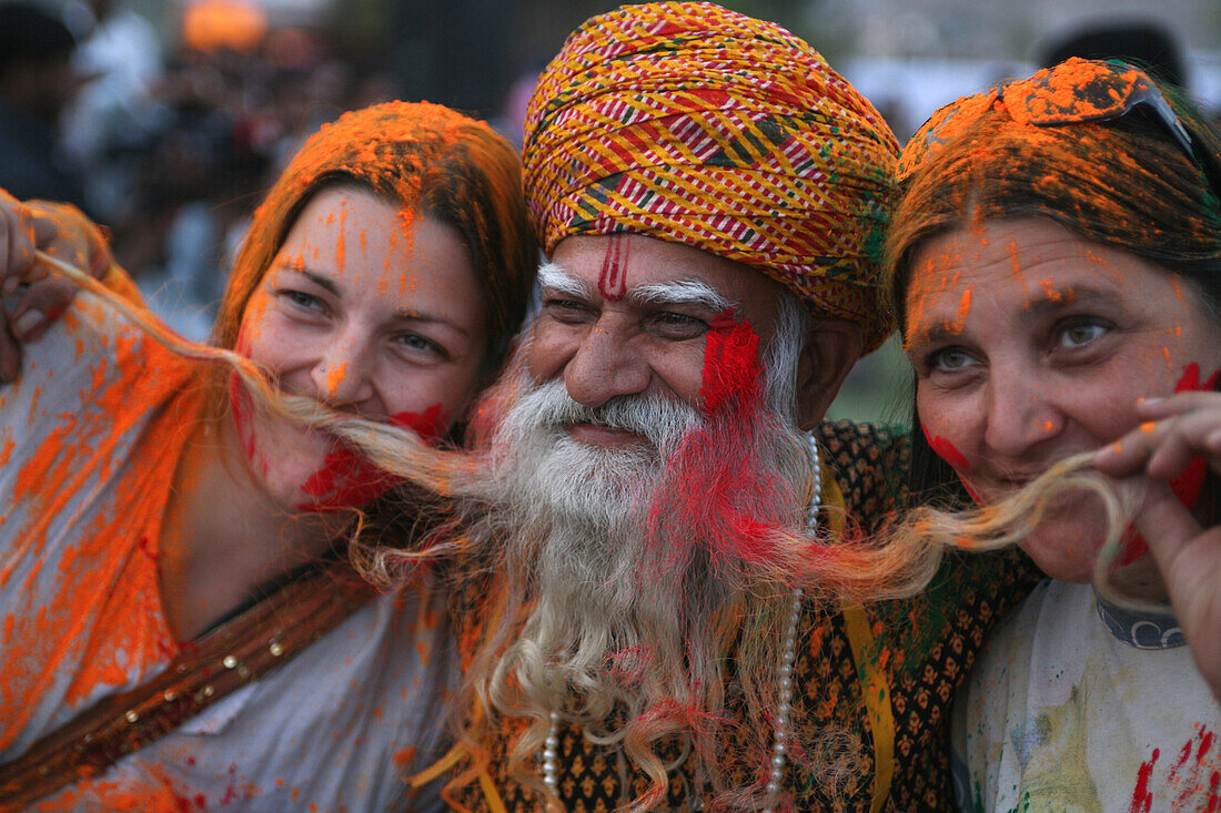 Cloured Dye On Female Tourists Who Pose With Rajasthani Guy With Long Beard At Elephant Festival, Jaipur, Rajasthan State, India. Asia