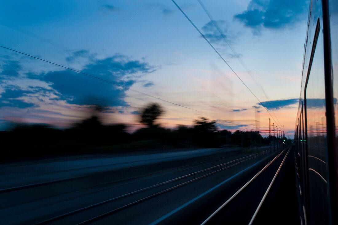 Looking out of window of train at sunset, blurred motion, France