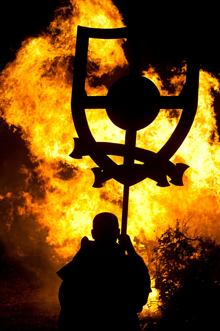 Man with banner dressed as monk in front of large bonfire, Lewes, East Sussex