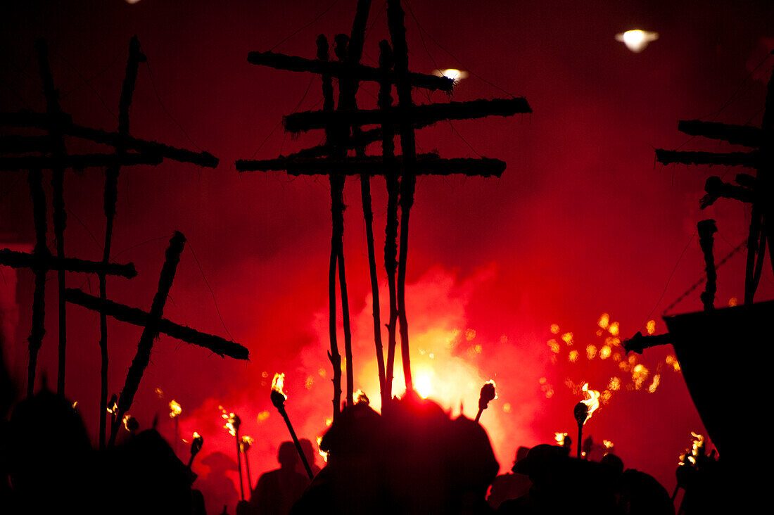 Silhouettes of 17 crosses  lit by red flares on the United Grand Procession, Lewes, East Sussex, England.  Seventeen crosses are carried to commemorate the 17 protestant martyrs killed on Lewes Hight Street between 1555 and 1557.