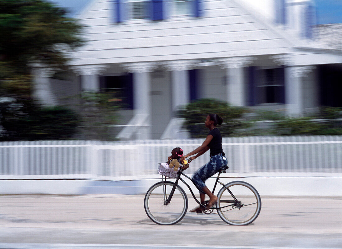 Woman riding bike along Bay Street, Dunmore Town, Harbour Island, Bahamas
