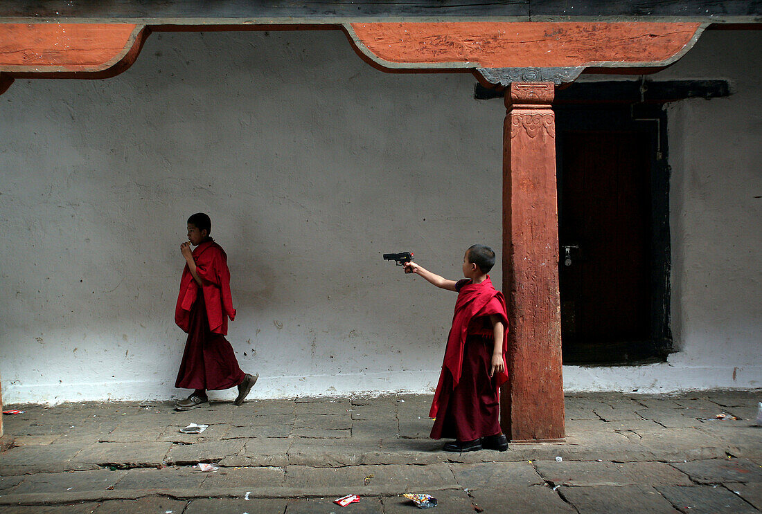 Bhutanese boy monk firing a toy gun, Wangdiphodrang, Bhutan
