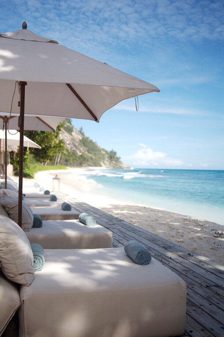 Outdoor beds on patio by beach, North Island, Seychelles