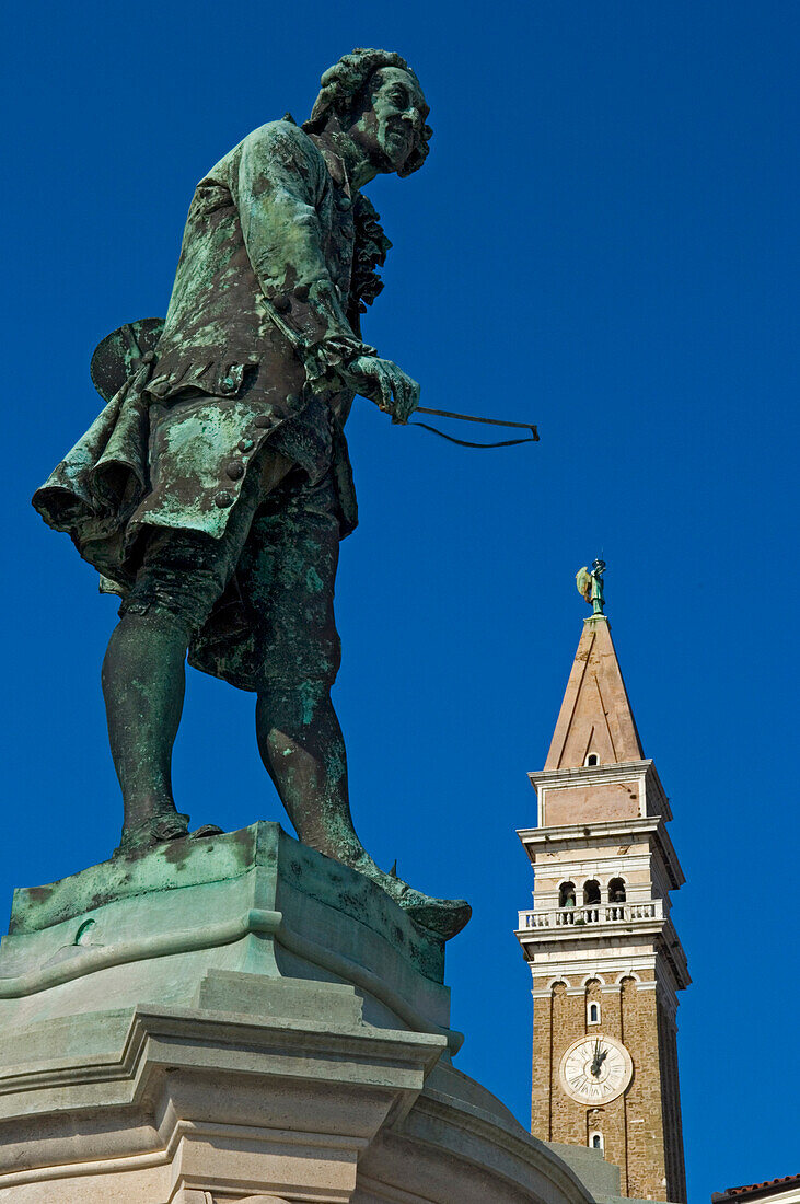 Statue of the local composer and violinist Giuseppe Tartini (1692-1770) and the clock tower of St. George's Cathedral, Piran, Slovenia.
