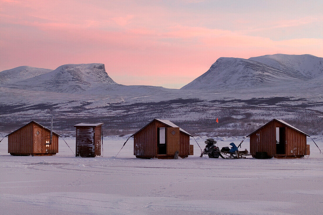 Abisko Ark Hotel cabins with Lapporten mountain range in background at dusk, Abisko, Sweden