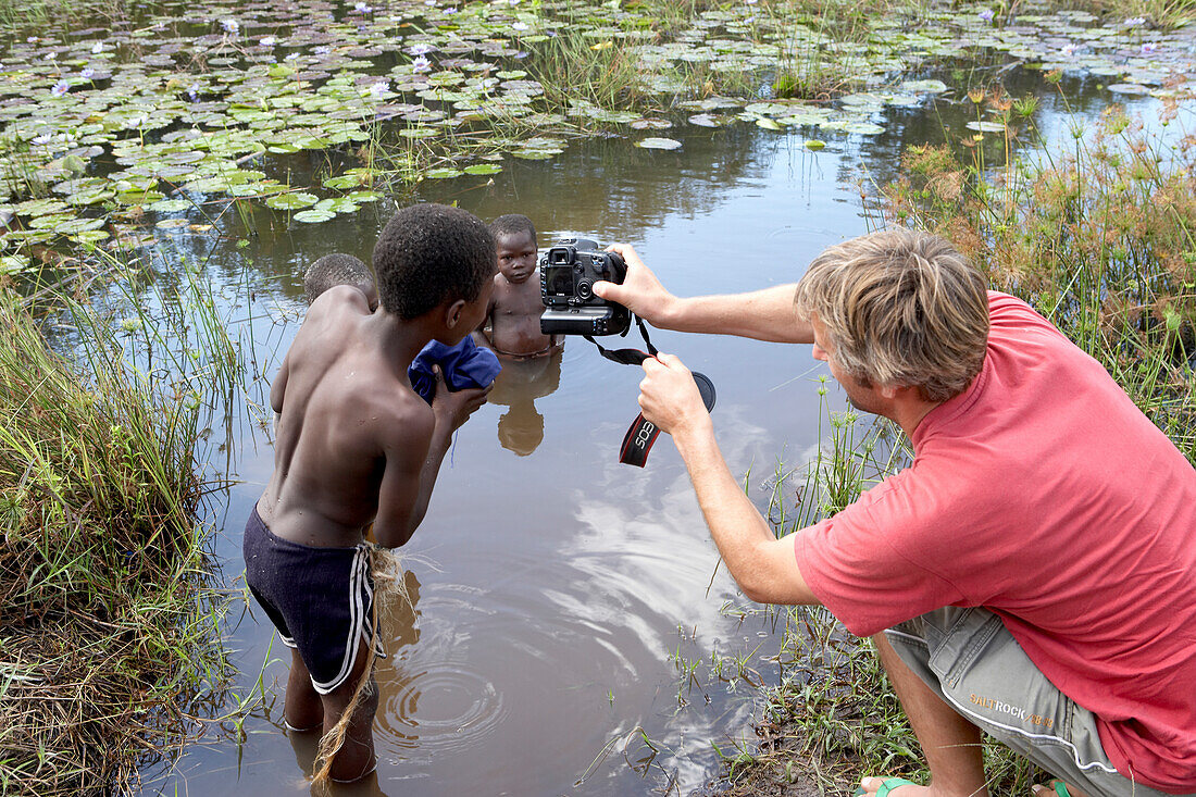 Photographer taking photos of children in river, Tanzania