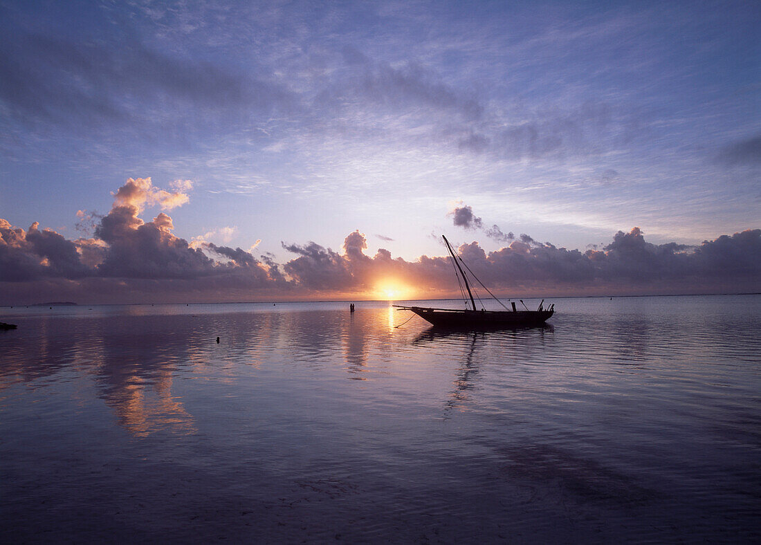Dhow in calm waters at low tide at dawn, Matemwe beach, Zanzibar, Tanzania.