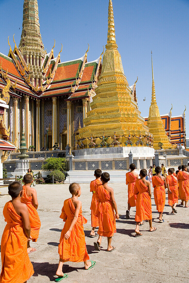 Young monks at Wat Phra Kaeo walking towards Royal Pantheon, Bangkok, Thailand
