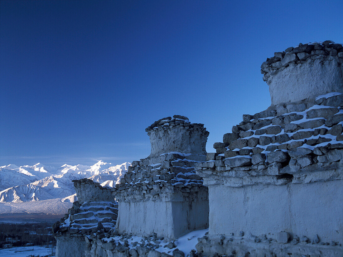 Chortens covered in snow beside Leh, looking over to Stok Kangri at dawn, Ladakh, India.