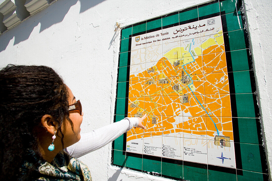 Female tourist looking at Medina map on wall, Tunis, Tunisia