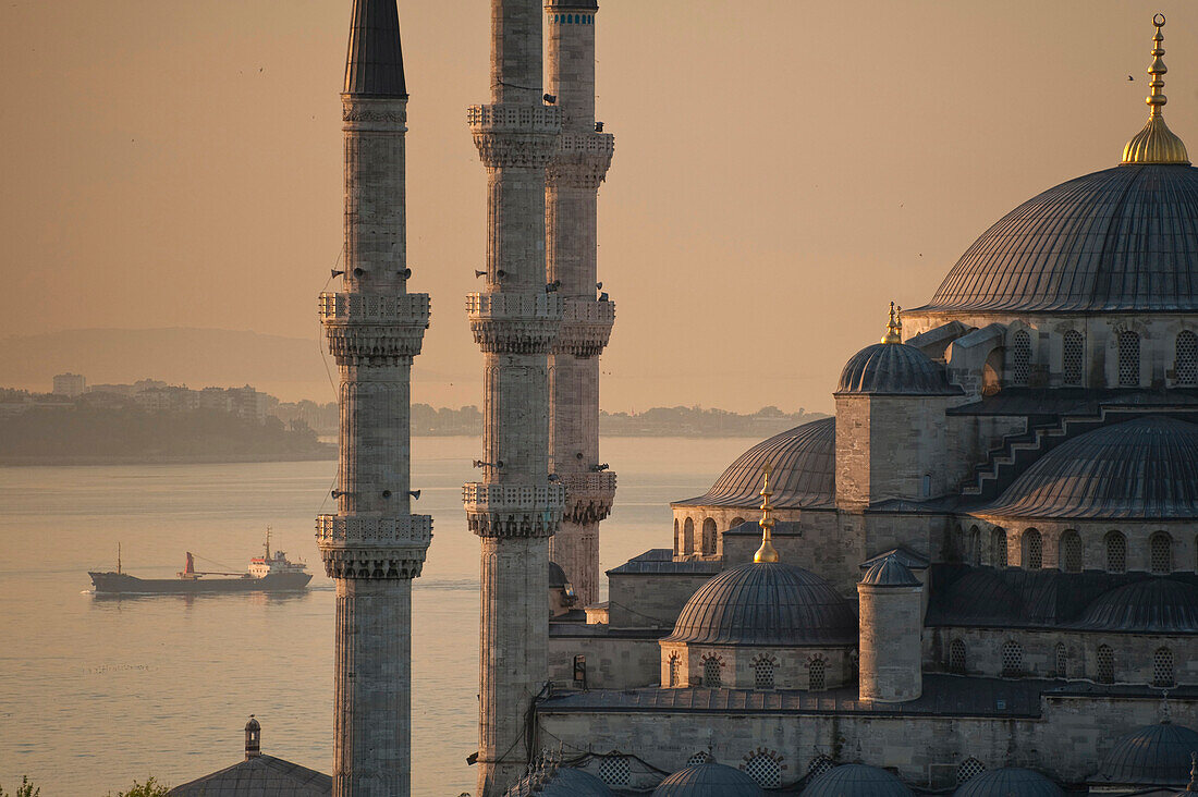 Ship sailing along the Bosphorus behind the Sultanahmet or Blue mosque at dawn, Istanbul, Turkey.