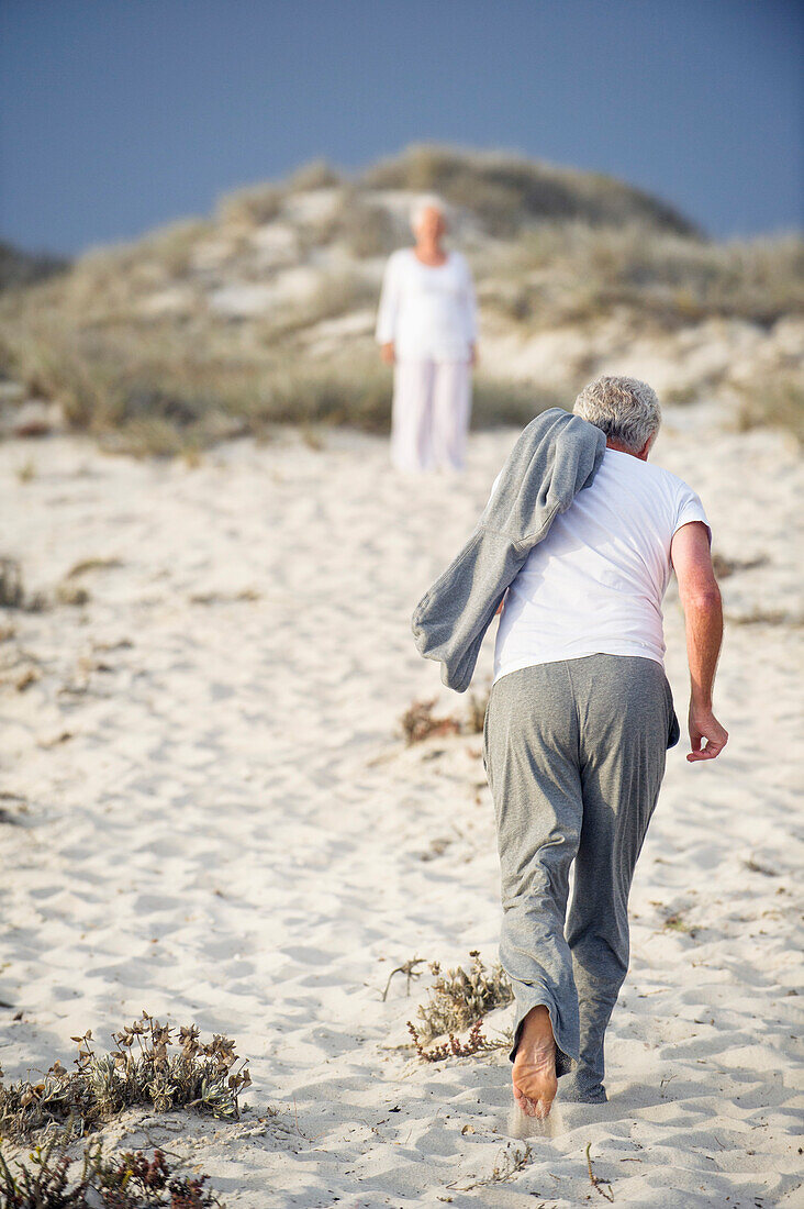 Rear view of a senior man running towards a woman standing in the background