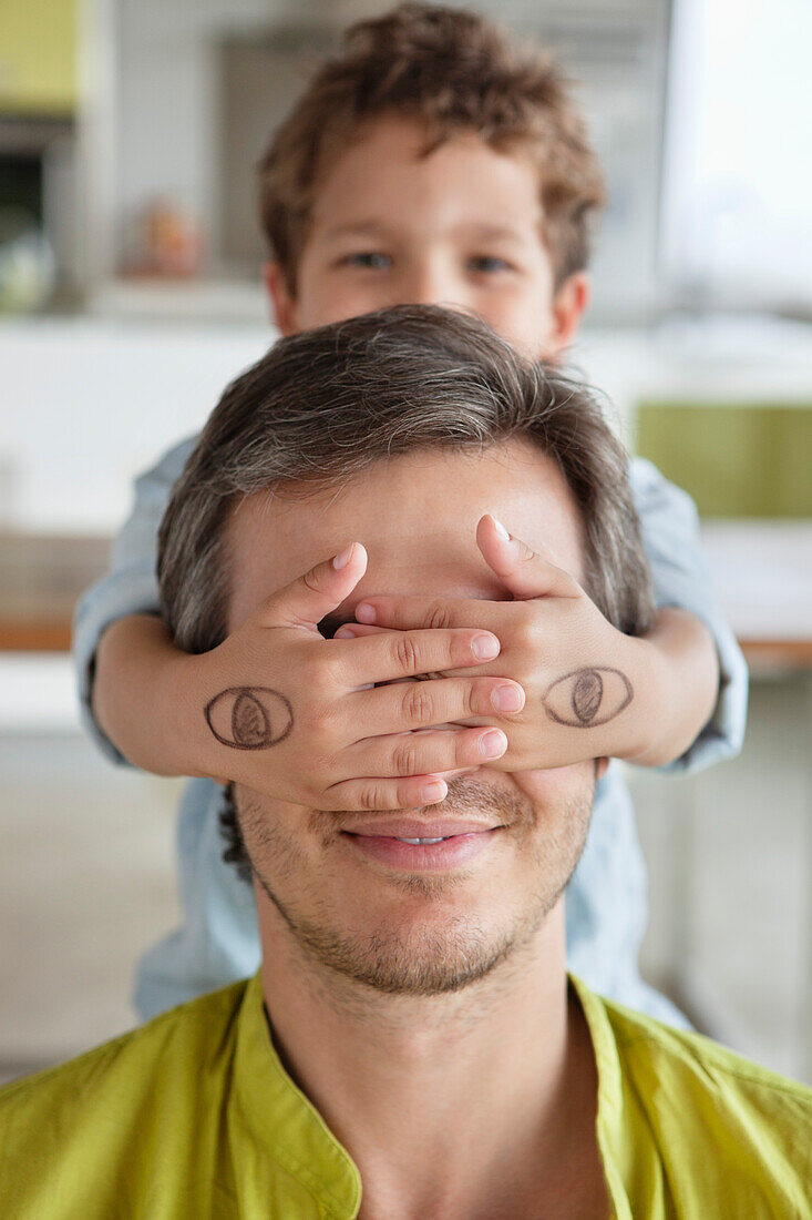 Boy covering his father's eyes