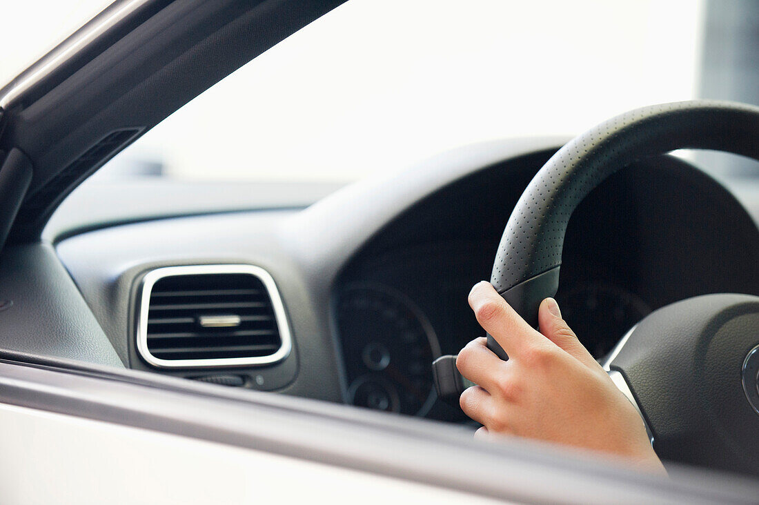 Close-up of a human hand on car steering wheel