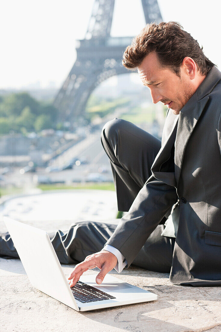 Businessman working on a laptop with the Eiffel Tower in the background, Paris, Ile-de-France, France