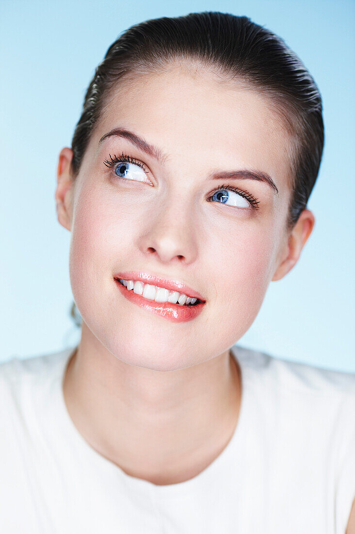 Portrait of young woman biting lips and looking up