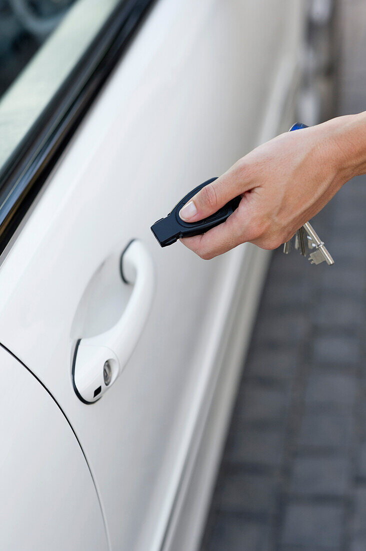 Person's hand unlocking the car with remote control