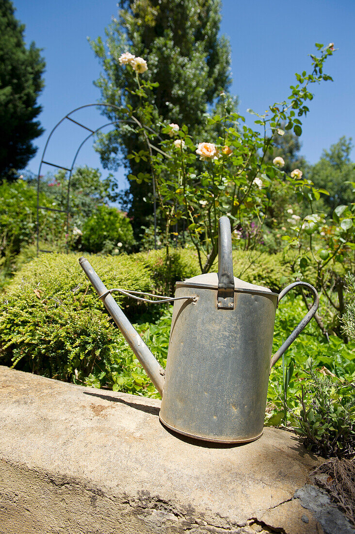 Watering can on a rock in a garden