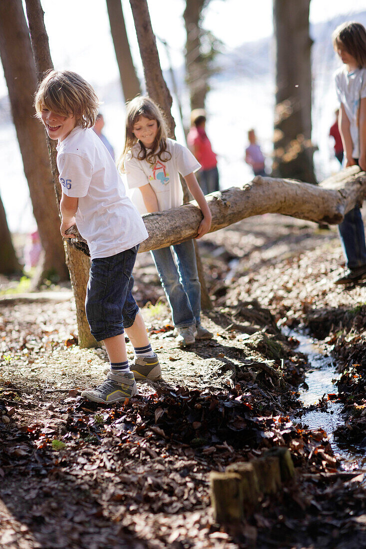 Children playing along the lakeshore, jumping over a stream, Leoni castle grounds, Leoni, Berg, Lake Starnberg, Bavaria, Germany