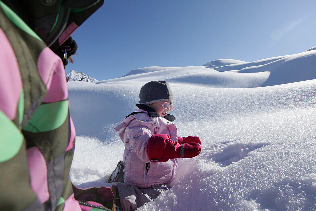 Two girls 12 and 2 years, playing in the snow, Kloesterle, Arlberg, Tyrol. Austria