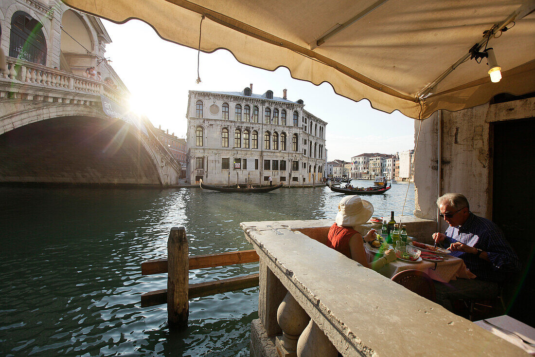 Elderly couiple enjoying a meal at the Rialto bridge, Venice, Veneto, Italy