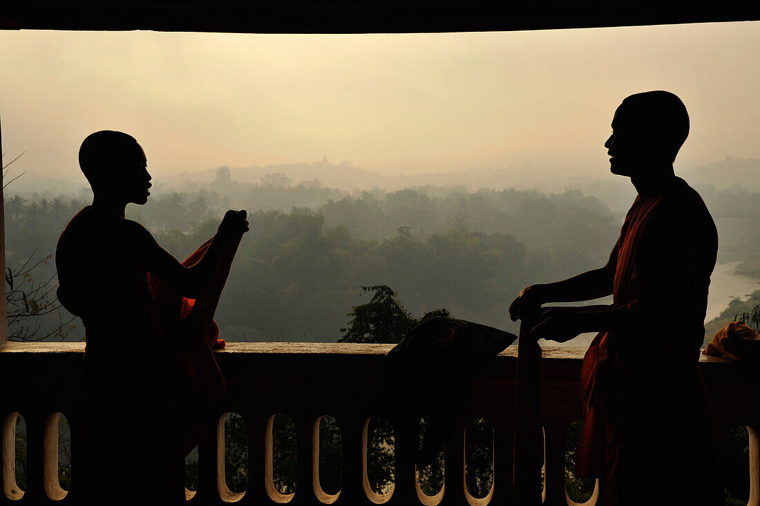 Junge Mönche, Novizen, legen ihre Roben zusammen, Blick über Hügel und Wald im Dunst, Phu Si Hügel, Luang Prabang, Laos, Südostasien, Asien