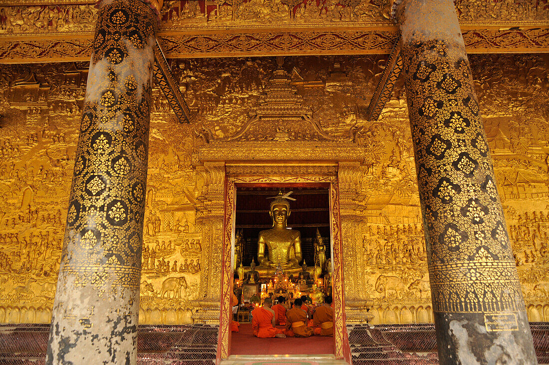Fassade mit vergoldetem Relief und Mönche bei der Abendandacht, Wat Mai Suwannaphumaham, Luang Prabang, Laos, Südostasien, Asien