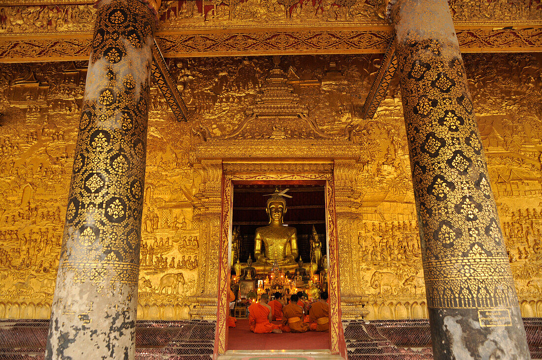 Gallery with golden relief and monks at evening prayer, Wat Mai Suwannaphumaham, Luang Prabang, Laos, Lao Peoples Democratic Republic