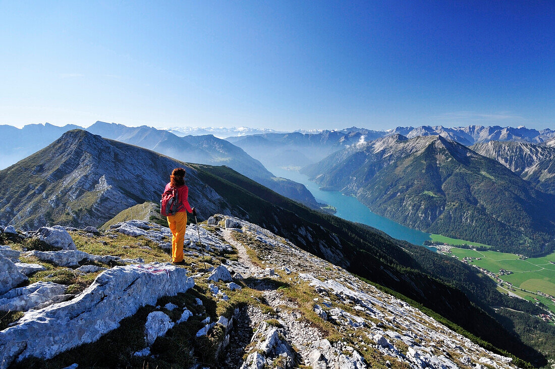 Woman walking at Unnutz with view to lake Achensee, Rofan mountain range and Alpine main ridge, Unnutz, Unnuetz, Rofan, Tyrol, Austria