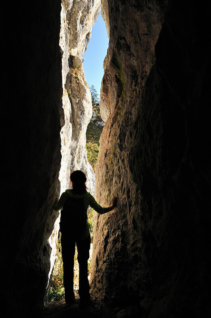 Woman passing through a crevice, Brunnstein, Bavarian Prealps, Upper Bavaria, Bavaria, Germany