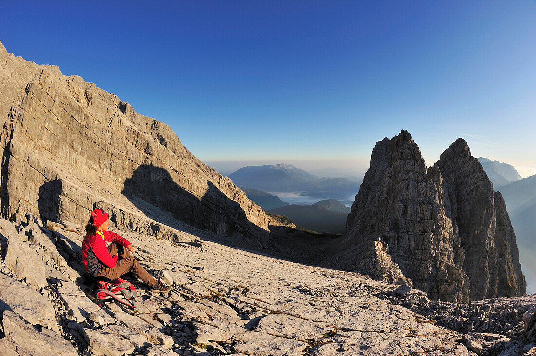 Frau sitzt am Dritten Watzmannkind,  Watzmann Mittelspitze, Viertes, Zweites und Erstes Watzmannkind im Hintergrund, Watzmann, Nationalpark Berchtesgaden, Berchtesgadener Alpen, Oberbayern, Bayern, Deutschland