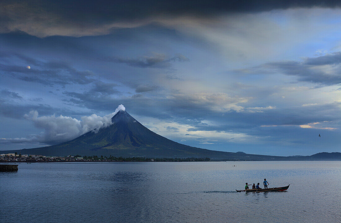 Young people on outrigger with steaming Mayon Volcano, Legazpi City, Luzon Island, Philippines, Asia