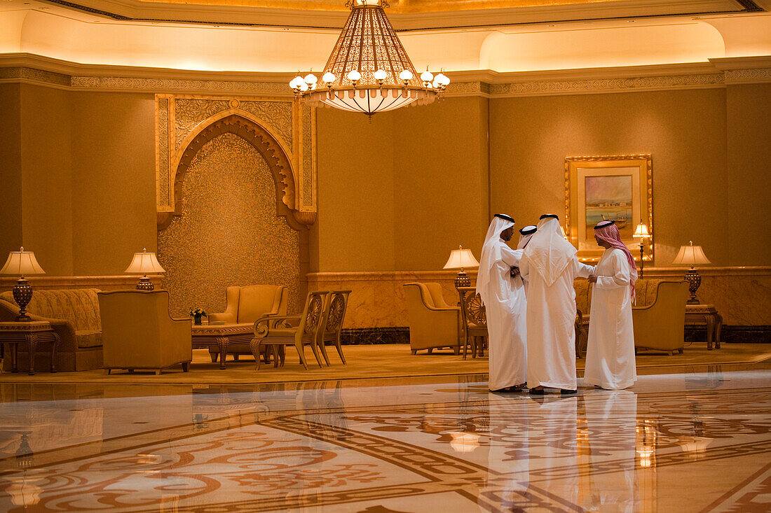 Geschäftsmänner in arabischen Gewändern stehen in der Lobby des Emirates Palace Hotel, Abu Dhabi, Vereinigte Arabische Emirate