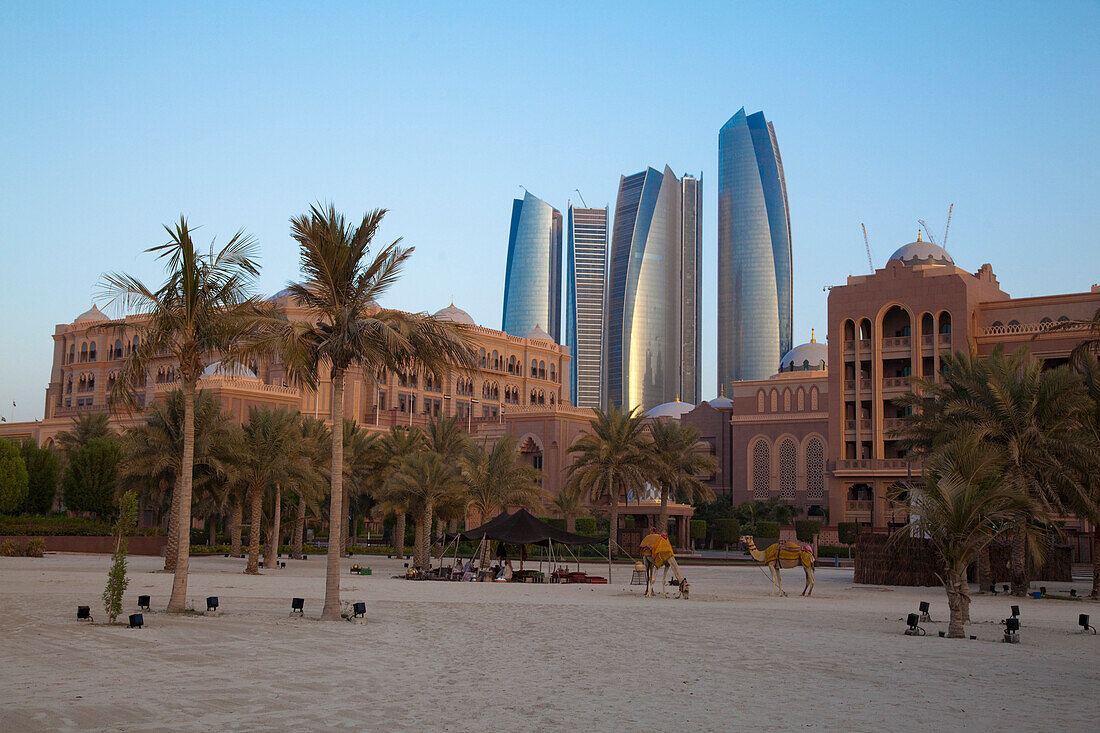 Strand und Palmen vor dem Emirates Palace Hotel mit Hochhäusern im Hintergrund, Abu Dhabi, Vereinigte Arabische Emirate
