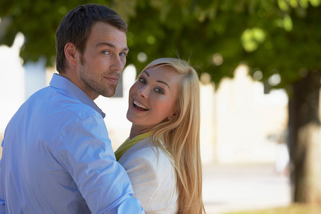 Young couple smiling to the camera, Schlossplatz, New Castle, Stuttgart, Baden Wurttemberg, Germany