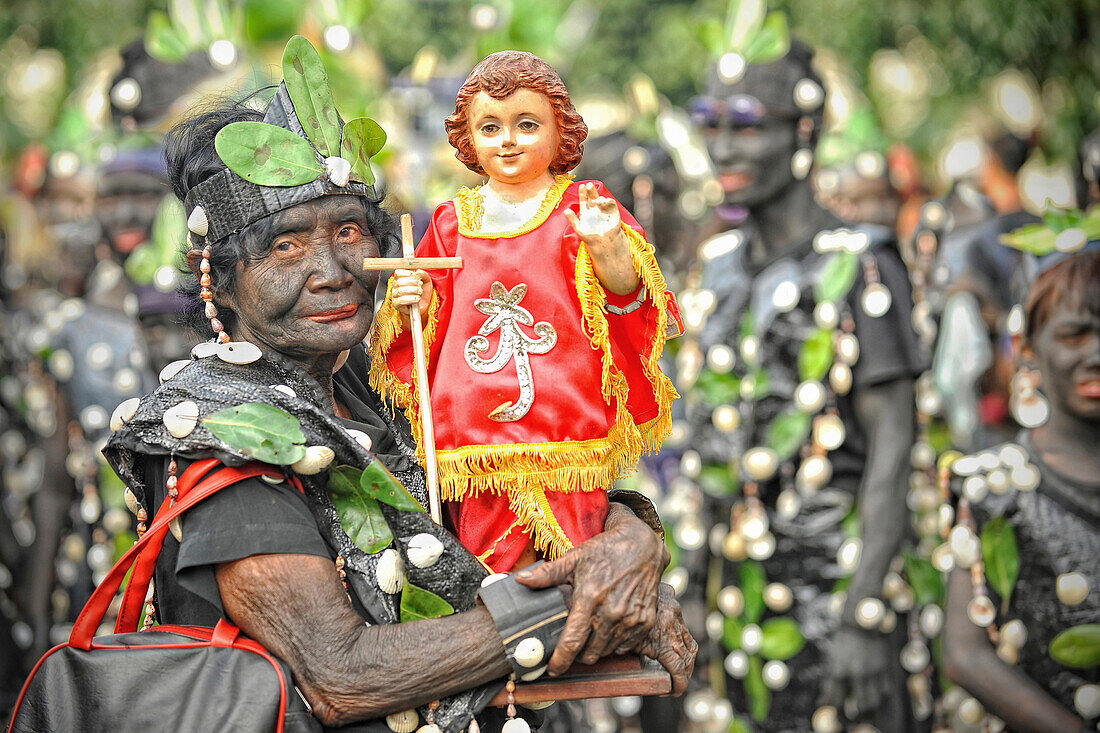 Old woman holding a Santo Nino figur, Ati Atihan festival, Kalibo, Aklan, Panay Island, Visayas, Philippines
