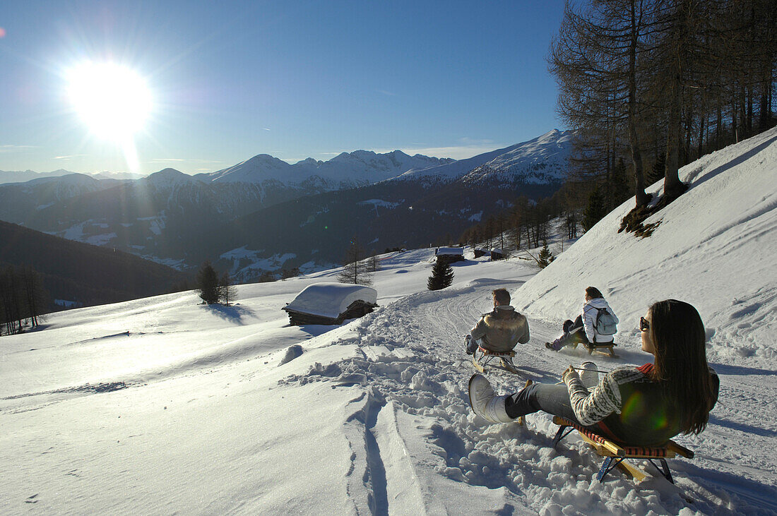 People sledding downhill in snowy mountain scenery, Alto Adige, South Tyrol, Italy, Europe