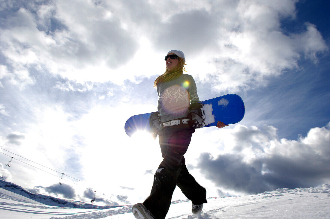 Junge Frau mit Snowboard unter Wolkenhimmel, Seiser Alm, Alto Adige, Südtirol, Italien, Europa