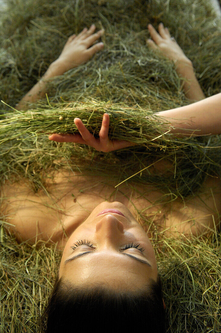 Young woman taking a hay bath, Alto Adige, South Tyrol, Italy, Europe