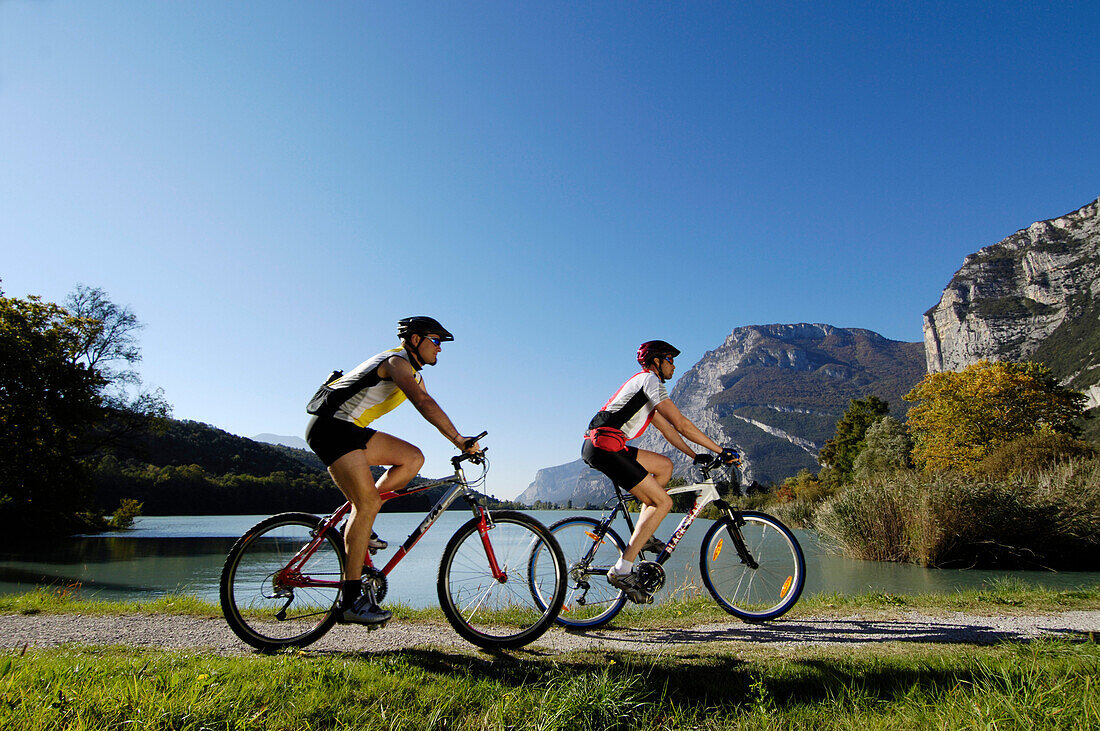 Mountainbiker am Ufer eines Sees im Sonnenlicht, Alto Adige, Südtirol, Italien, Europa