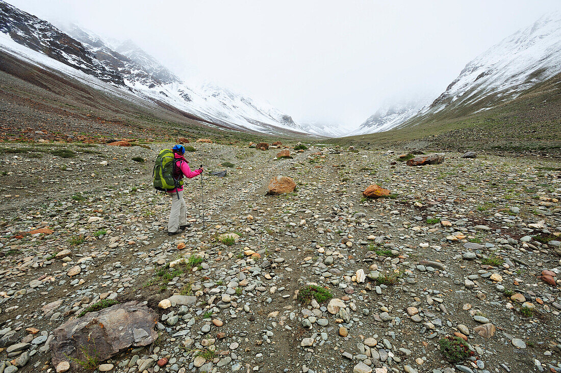 Frau mit Rucksack überquert Geröllfeld, Lakang Sumdo, Großer Zanskar Trek, Zanskargebirge, Zanskar, Ladakh, Jammu und Kashmir, Indien