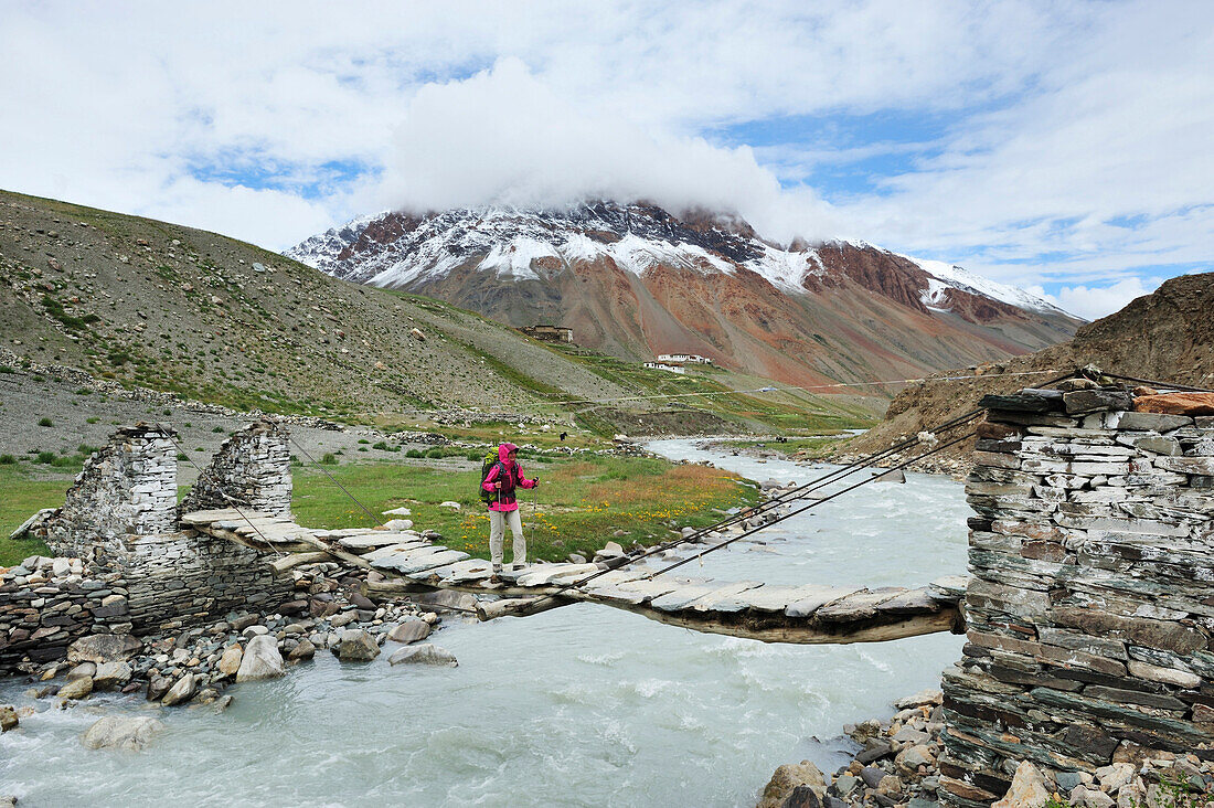 Frau überquert Fluß auf einer Hängebrücke bei She, zwischen Testa und Lakang Sumdo, Großer Zanskar Trek, Zanskargebirge, Zanskar, Ladakh, Jammu und Kashmir, Indien