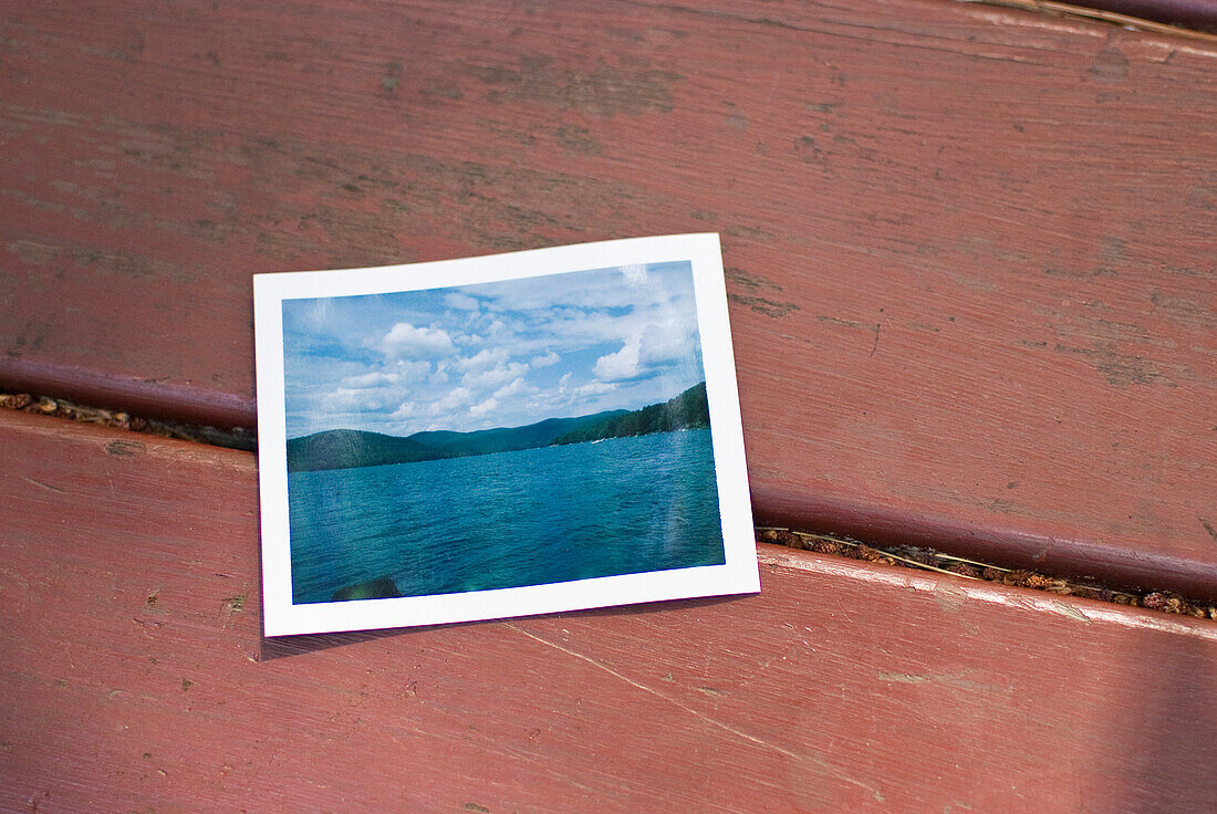 Polaroid of Scenic Lake on Red Picnic Table