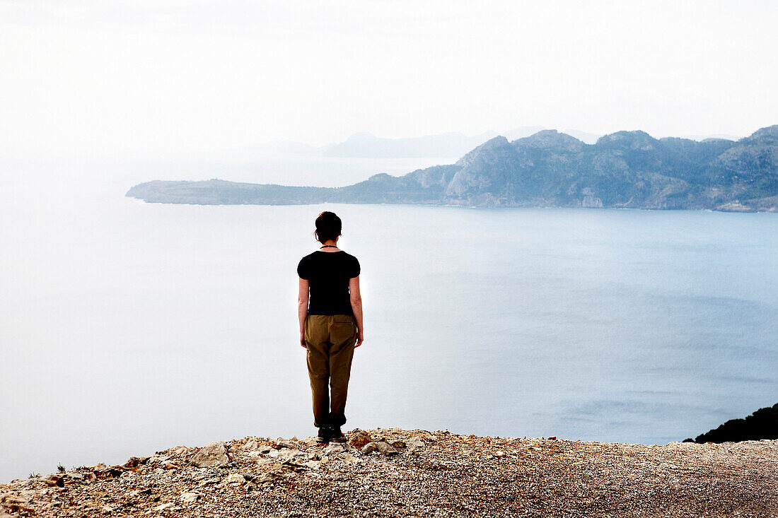 Woman Standing at Edge of Cliff Facing Mediterranean Sea, Mallorca, Spain